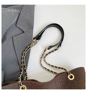 Dettaglio borsa tote in tessuto glitterato con tracolla a catena nero e oro