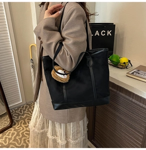 Détail d'un grand sac cabas noir en toile avec pendentif en peluche et garniture