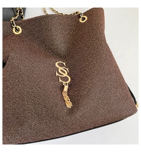 Dettaglio ravvicinato della borsa glitter marrone con catena dorata e logo metallico
