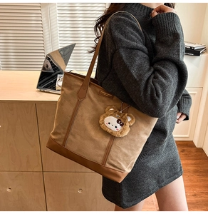 Détail du sac cabas en toile avec base en cuir marron et breloque ours en décor de bureau