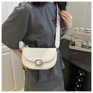 Detail of cream saddle bag featuring a rhinestone G buckle and wide geometric strap