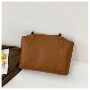 Détail des coutures contrastées blanches sur le sac fourre-tout en cuir marron et boucles dorées
