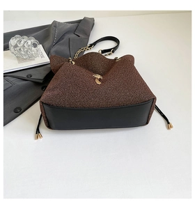 Dettaglio della borsa in tweed e pelle nera con catena dorata e decoro in metallo