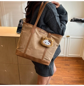 Détails du sac fourre-tout en daim marron avec pendentif peluche dans un bureau cosy