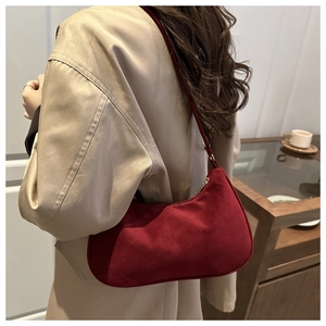 Detail shot of burgundy suede baguette bag worn with a chic beige blazer outfit