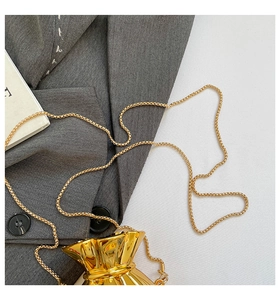 Dettaglio mini borsa a forma di sacchetto portafortuna con catena dorata su blazer