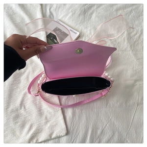 Detail view of pink mini bag interior with magnetic clasp and pearl chain handle
