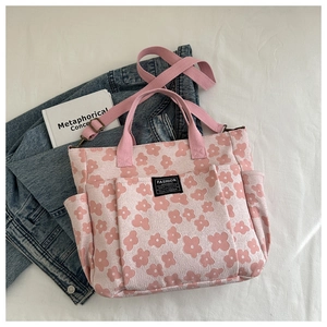 Detail of floral canvas tote with multi-pocket design and adjustable shoulder strap