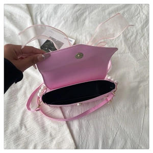 Detail showing pink bag interior with black lining, magnetic clasp, and pearl handle