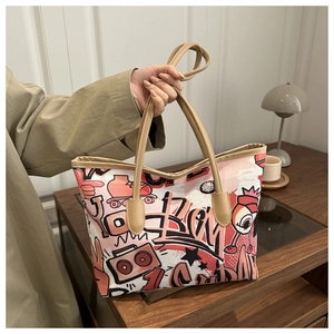 Detail of graffiti tote bag showing street art patterns and brown leather handles