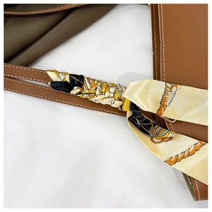 Détail de la bandoulière en cuir marron avec un foulard en soie jaune à motifs vintage