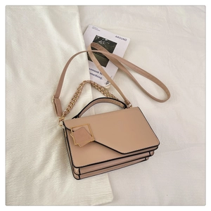 Detail view of beige crossbody bag with gold square buckle and stylish chain strap