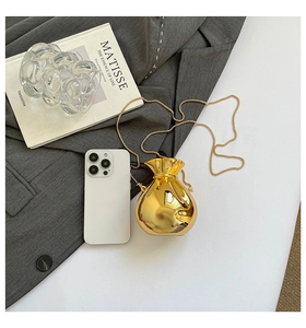 Dettaglio mini borsa portafortuna dorata a specchio con una catena sottile elegante