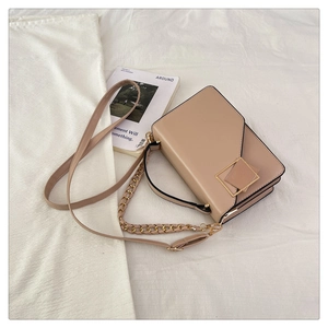 Detail of beige square bag with gold geometric buckle and metallic chain strap