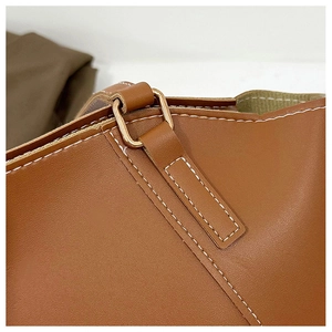 Détail d'un cabas en cuir marron avec surpiqûres blanches et boucle dorée carrée