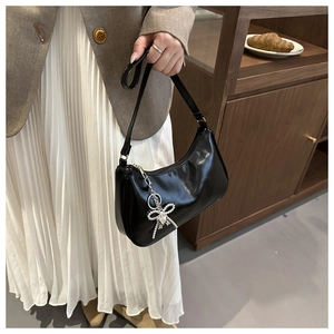 Dettaglio borsa hobo nera lucida in ecopelle con ciondolo a farfalla in argento