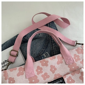 Detailed close-up of pink floral canvas tote bag with adjustable woven straps and fashion tag