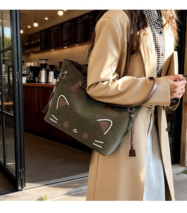 Detail of dark green canvas tote bag with cartoon cat print and brown leather fringe