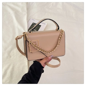 Detail of beige small square bag with chunky gold chain and smooth faux leather texture