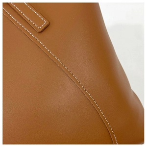 Gros plan sur un sac cabas en cuir marron avec texture premium et surpiqûres blanches