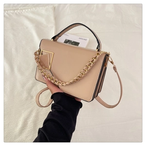 Detail of beige faux leather handbag featuring a gold geometric buckle and chain strap