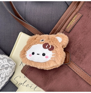 Détail d'un joli charms Hello Kitty en peluche sur un sac cabas en daim marron