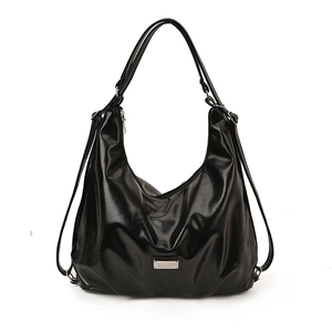 Glossy black versatile backpack and shoulder bag with metallic logo on white background