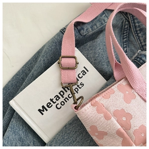 Detail view of pink floral canvas tote with vintage bronze buckle and woven shoulder strap