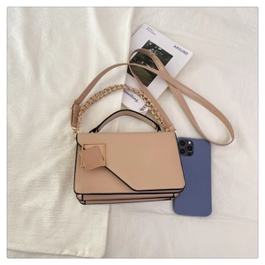 Top-down view of a beige crossbody bag with gold chain strap next to a smartphone