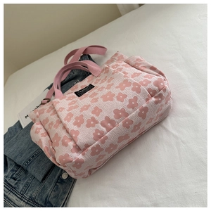 Pink floral tote bag with textured flower pattern and adjustable shoulder strap detail