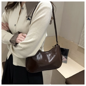 Dettaglio della borsa sottobraccio marrone scuro lucido con zip dorata e finitura laccata