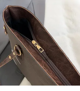 Detail of the high-quality gold metal zipper on a dark brown textured tote bag