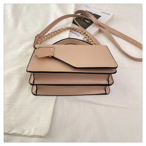 Detail of light beige three-layer bag with asymmetric flap and golden square buckle