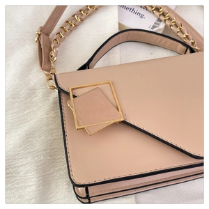 Detailed side view of the beige chain handbag showing gold metal lock and accordion pleats