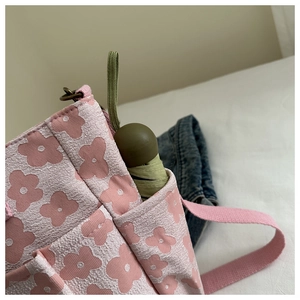 Detail of pink floral canvas bag featuring a side pocket with a dark green folding umbrella