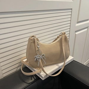 Beige half-moon underarm bag with silver bead bow charm on smooth PU leather finish