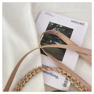 Close-up of beige leather strap woven with gold metal chain for a stylish handbag