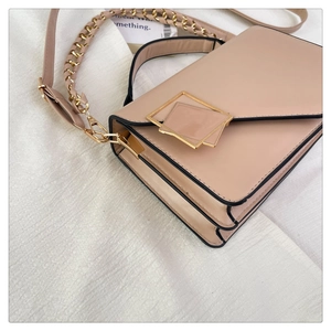 Detail view of pink flap bag with metallic square buckle and accordion side gussets
