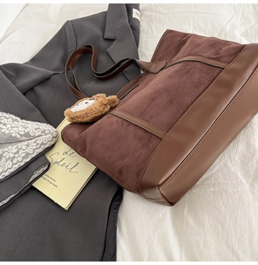 Vue latérale d'un grand sac cabas en daim marron sur tissu blanc avec blazer élégant