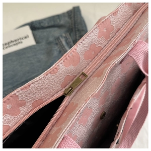 Top zipper close-up of pink floral fabric tote with bronze metal hardware and inner pocket