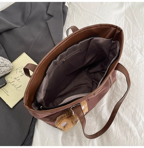 Détail de l'intérieur du cabas marron avec compartiment zippé et pendentif peluche