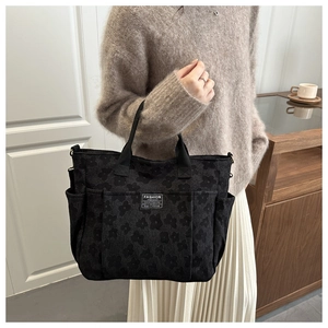 Detail of black floral jacquard tote bag with multiple pockets and fashion logo label