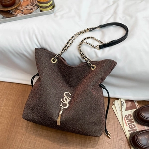 Borsa tote marrone metallizzato con logo S dorato e tracolla su uno sfondo vintage