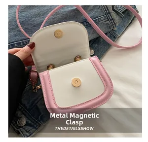 Detail of a white and pink mini crossbody bag showing its secure magnetic snap closure