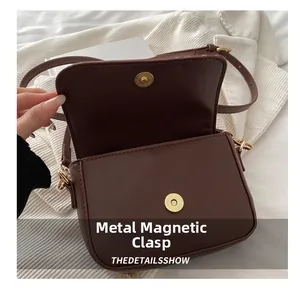 Close-up of brown faux leather crossbody bag featuring a golden magnetic snap closure