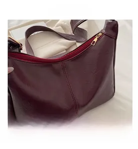 Detailansicht der weinroten Kunstledertasche mit Kieselstruktur und goldener Hardware