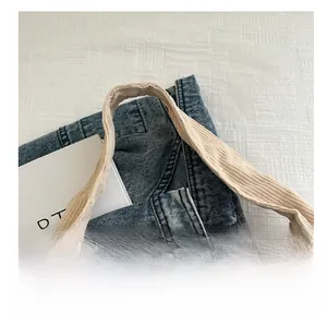 Détail de la poignée en velours côtelé et du denim bleu lavé sur le grand sac cabas