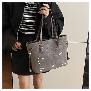 Detailed view of the cute cat face pattern and tassels on the grey leather tote bag