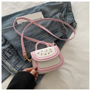 Close-up of pink cherry pattern mini crossbody bag on white linen with denim jacket