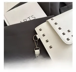 Detail view of white lychee leather texture with square metal rivets and hardware